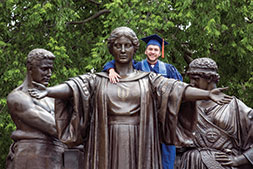 Photo of graduate posing with statue. Link to What to Give